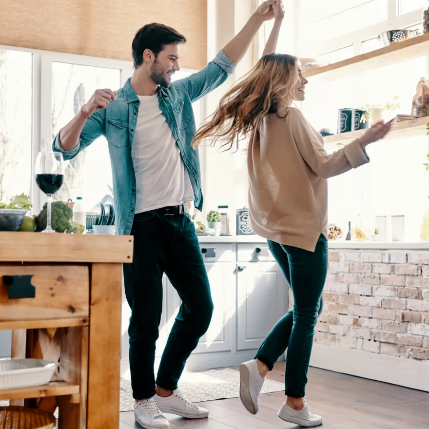 Pareja bailando en la cocina de su casa equipada